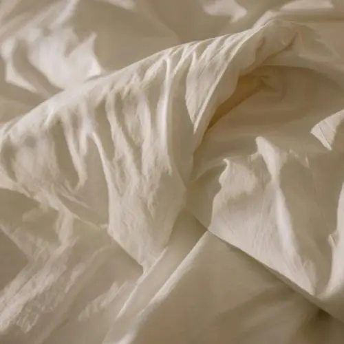 A close-up view of a pristine white bed adorned with a smooth, white cotton creating a serene and minimalist atmosphere.<br />
