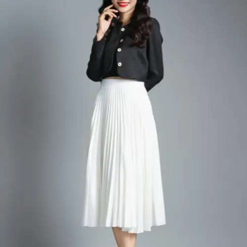 A woman wearing a black top and a white skirt stands confidently, showcasing a stylish and elegant outfit.<br />
