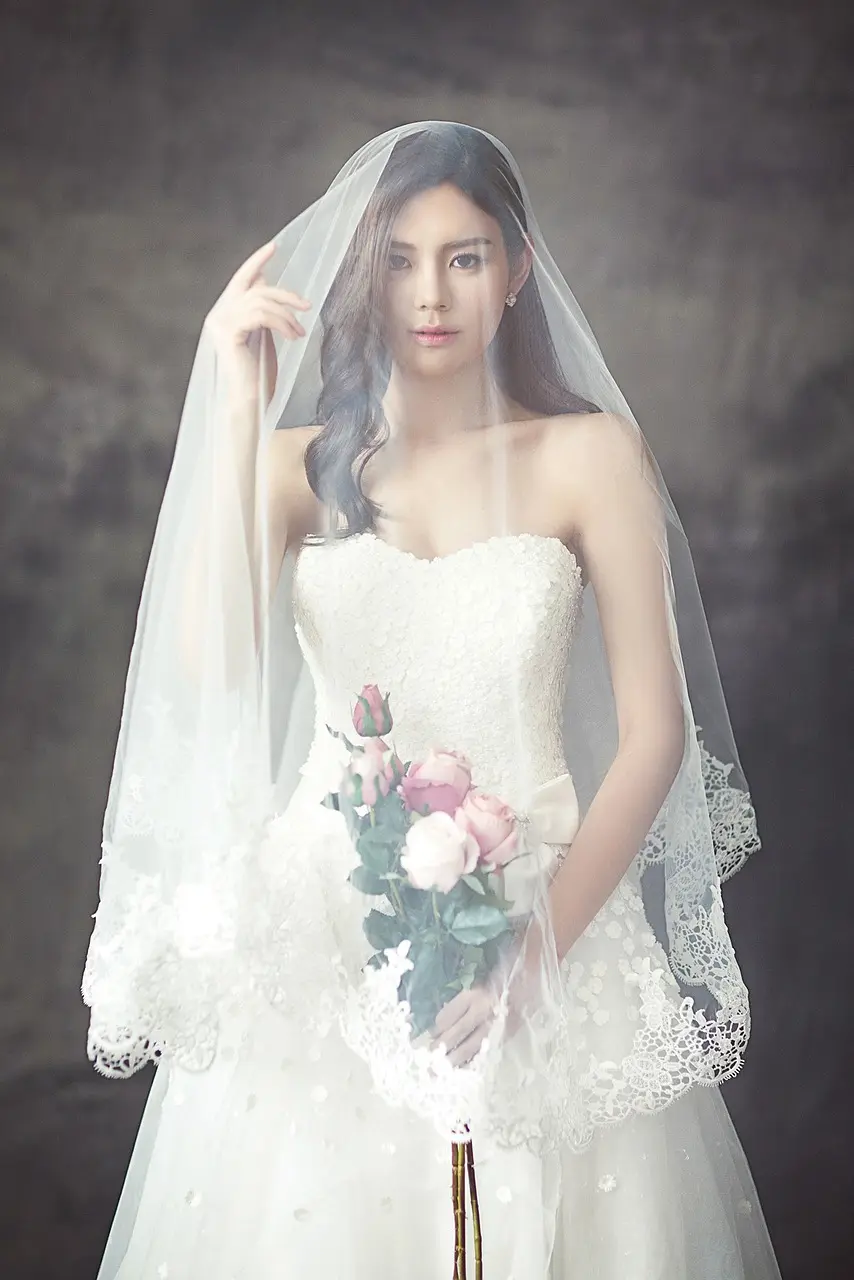 . A woman in a beautiful wedding dress gracefully holds a vibrant bouquet, radiating joy on her special day.